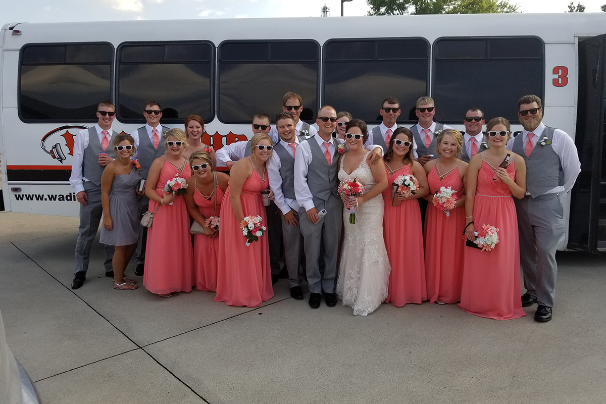 wedding party in front of a Wad It Up Transport and D J Service bus