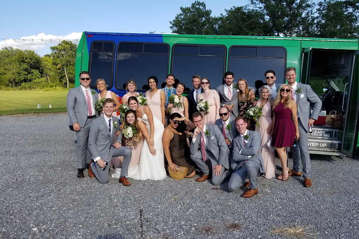 Another wedding party in front of a Wad It Up Transport and D J Service bus