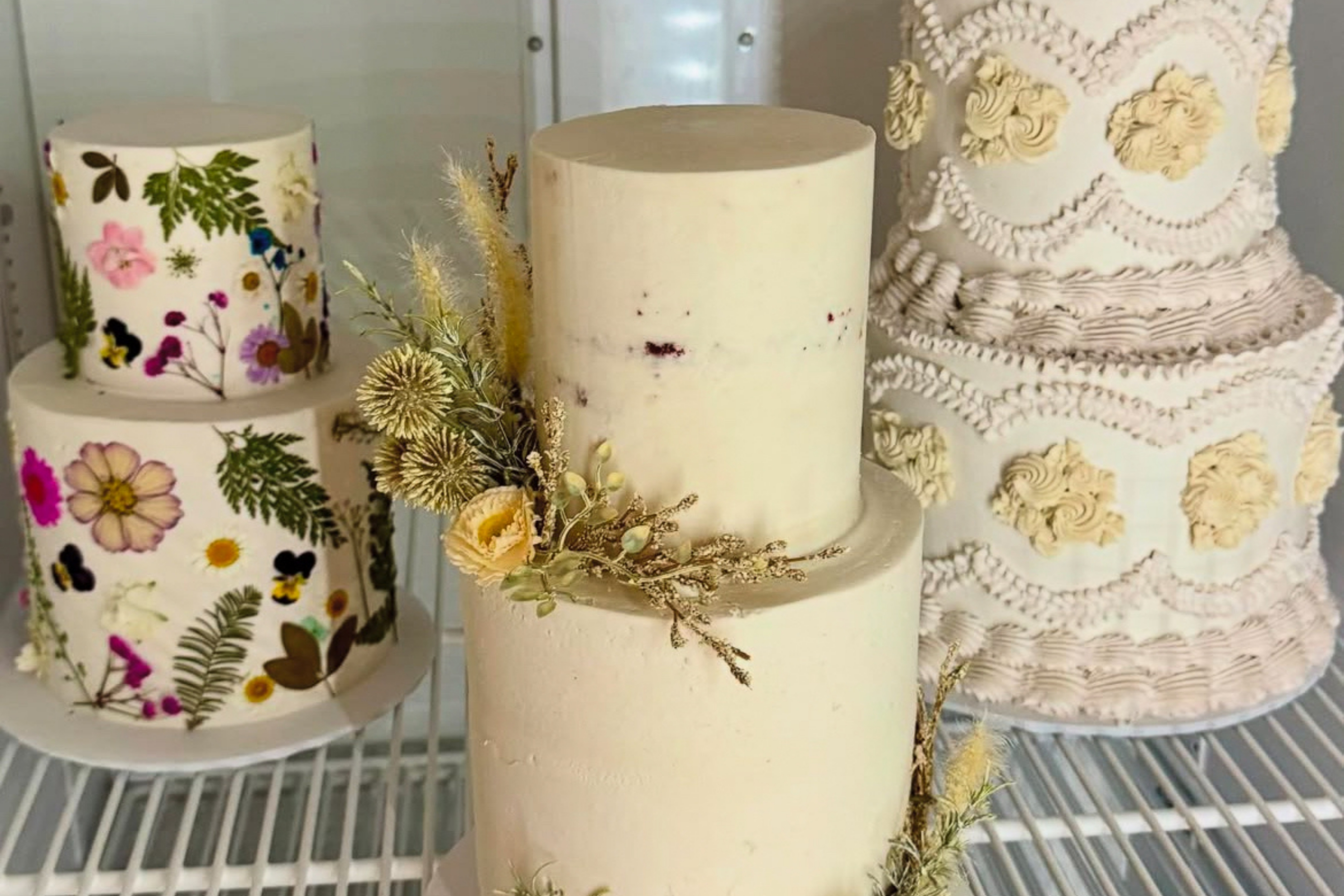 3 ornate cakes in a fridge