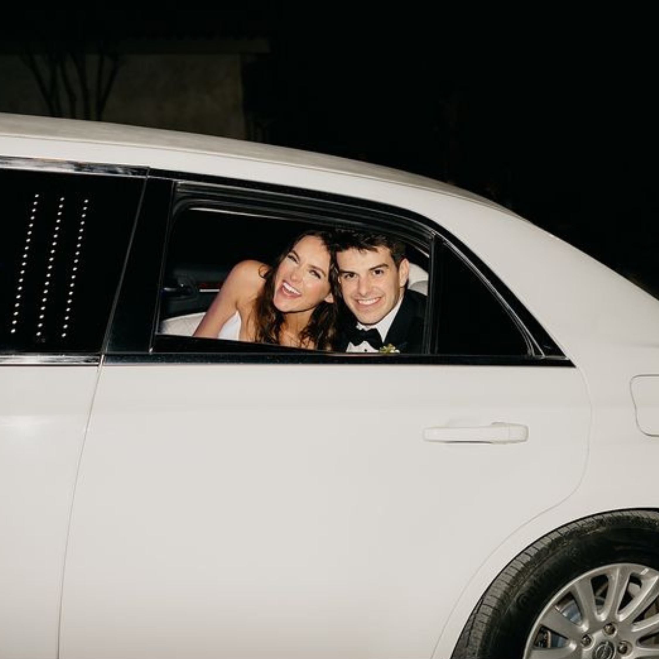 bride and groom smiling out a limo window