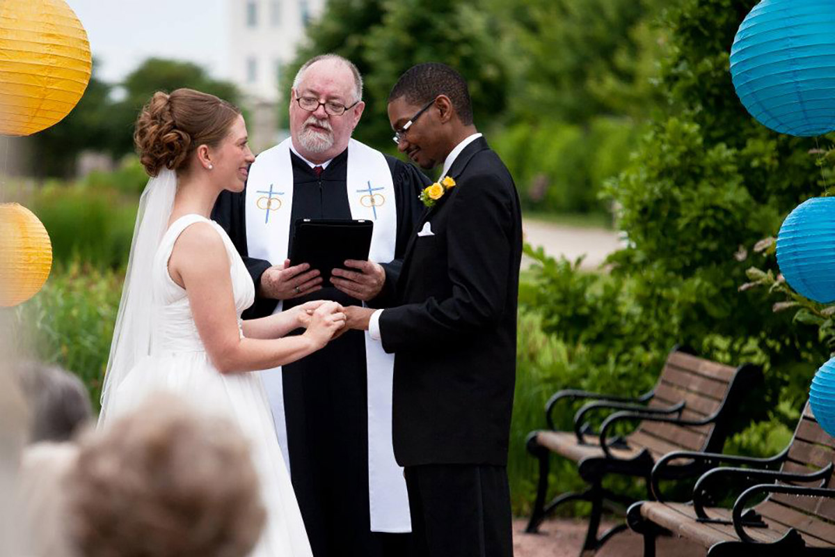 The Marrying Rev reciting wedding vows to another bride and groom at an outdoor wedding