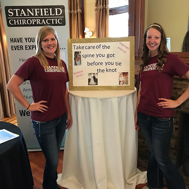 two employees from Stanfield Chiropractic standing next to their exhibit