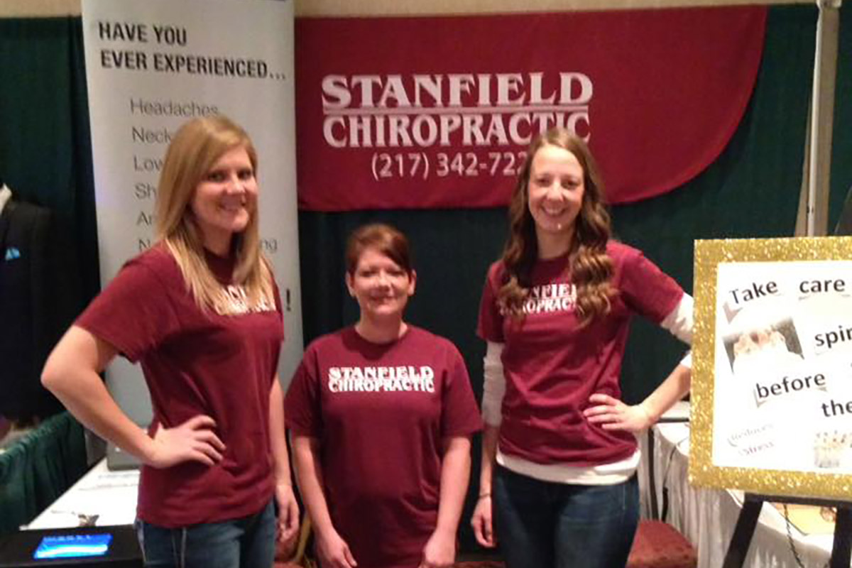 three Stanfield Chiropractic staff members standing at a show booth